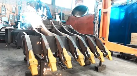 image of an employee welding a excavator rake